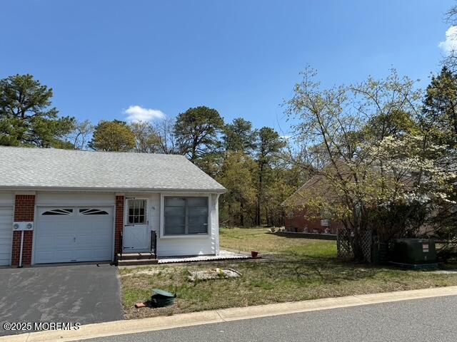 exterior space with an attached garage, a front lawn, brick siding, and aphalt driveway