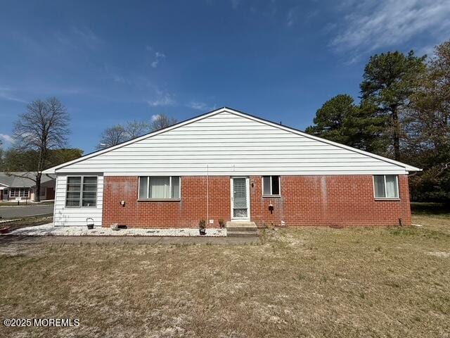 rear view of property featuring a lawn, brick siding, crawl space, and entry steps
