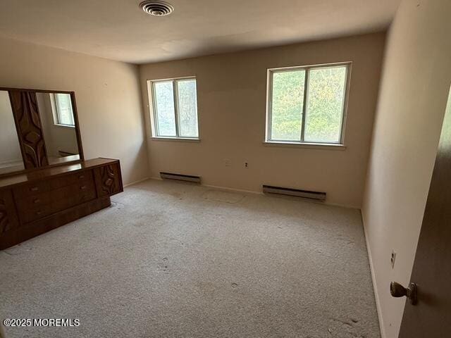 unfurnished bedroom featuring visible vents, baseboard heating, baseboards, a baseboard radiator, and carpet flooring