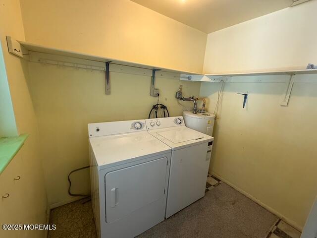 clothes washing area with laundry area, washer and clothes dryer, water heater, and light colored carpet