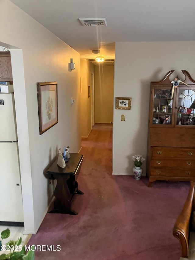 hall with carpet floors, visible vents, and baseboards