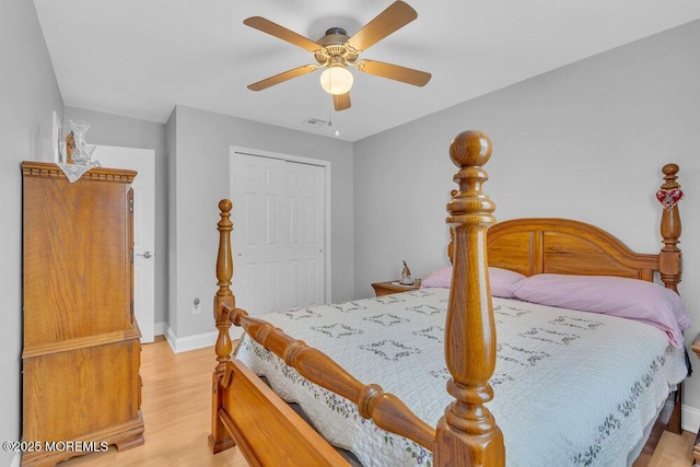 bedroom featuring baseboards, light wood-type flooring, ceiling fan, and a closet