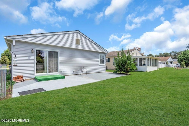 rear view of property with a lawn, a patio area, and a sunroom