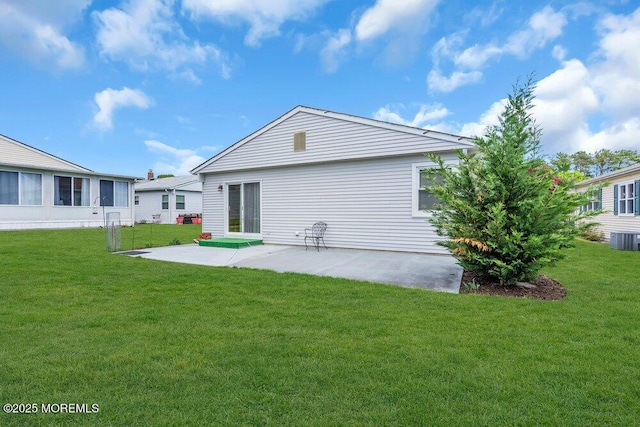 rear view of house with central air condition unit, a patio, and a yard