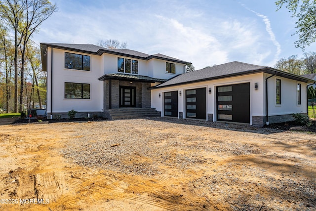 view of front of house with a garage, stucco siding, a standing seam roof, driveway, and metal roof