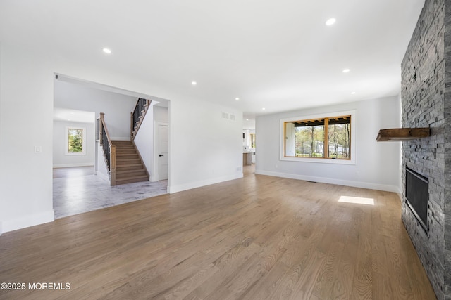 unfurnished living room with recessed lighting, stairway, visible vents, and a stone fireplace
