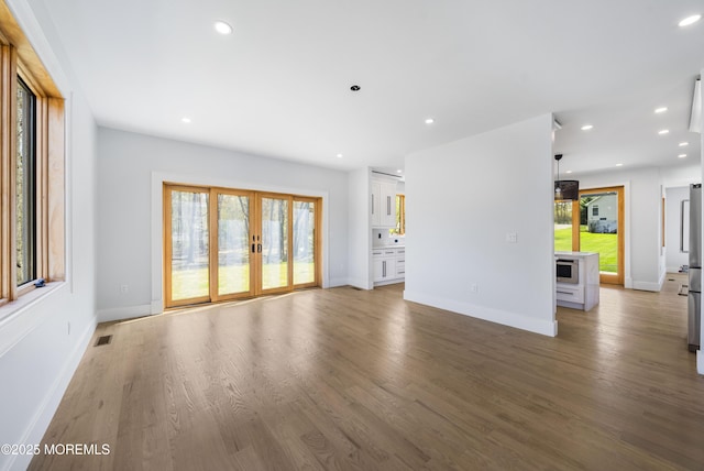 unfurnished living room featuring baseboards, wood finished floors, visible vents, and recessed lighting