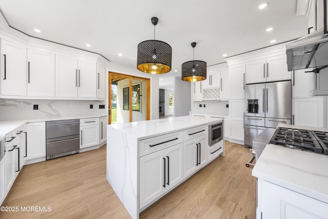 kitchen with recessed lighting, high end fridge, a kitchen island, and white cabinetry