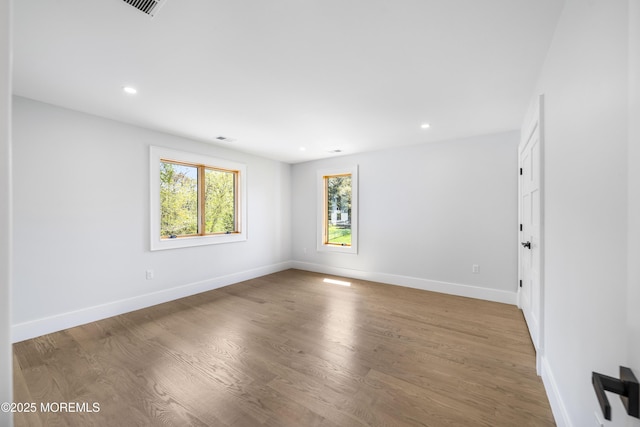 empty room with recessed lighting, wood finished floors, visible vents, and baseboards
