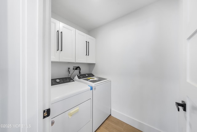 washroom featuring cabinet space, independent washer and dryer, light wood finished floors, and baseboards