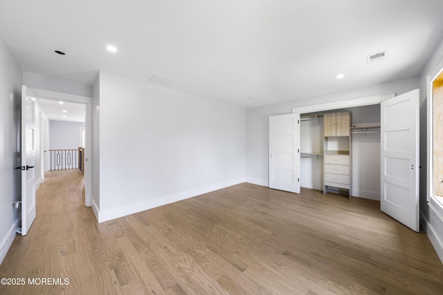 unfurnished bedroom featuring wood finished floors, a closet, baseboards, visible vents, and recessed lighting