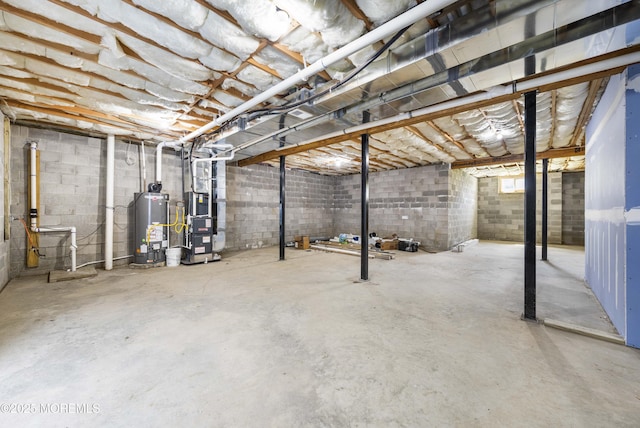basement featuring water heater, concrete block wall, and heating unit