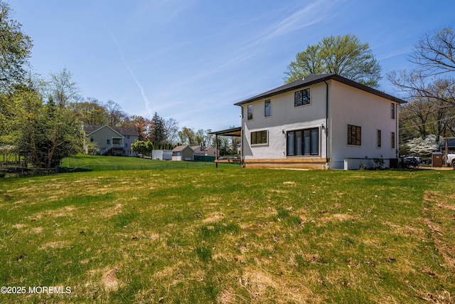 rear view of property featuring a yard and stucco siding
