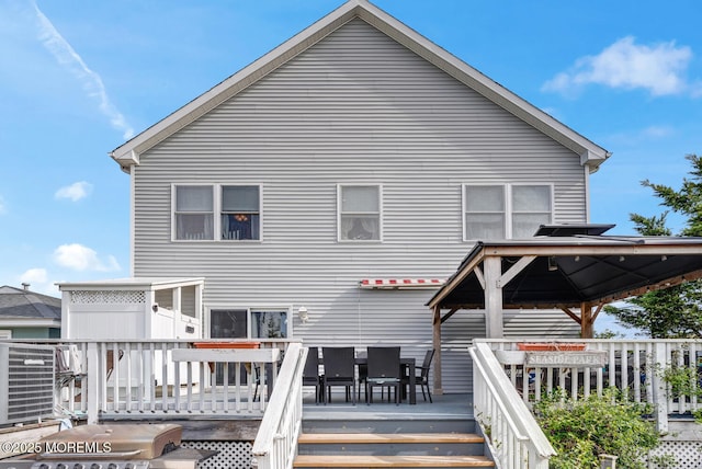 rear view of house with outdoor dining area, a gazebo, and a deck