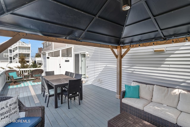 wooden terrace with a gazebo, outdoor dining space, and an outdoor hangout area