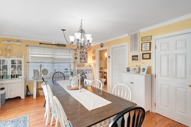 dining space featuring ornamental molding, light wood finished floors, and a chandelier