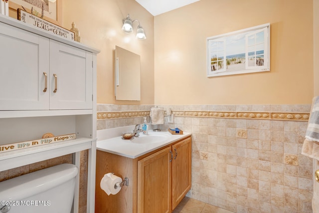 bathroom featuring vanity, tile patterned flooring, wainscoting, toilet, and tile walls