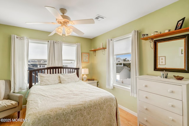 bedroom with baseboards, visible vents, multiple windows, and light wood-style flooring