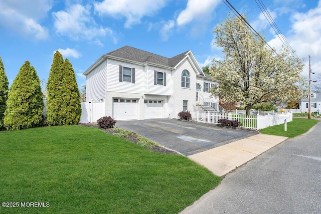 view of front of home with fence private yard, an attached garage, driveway, and a front lawn