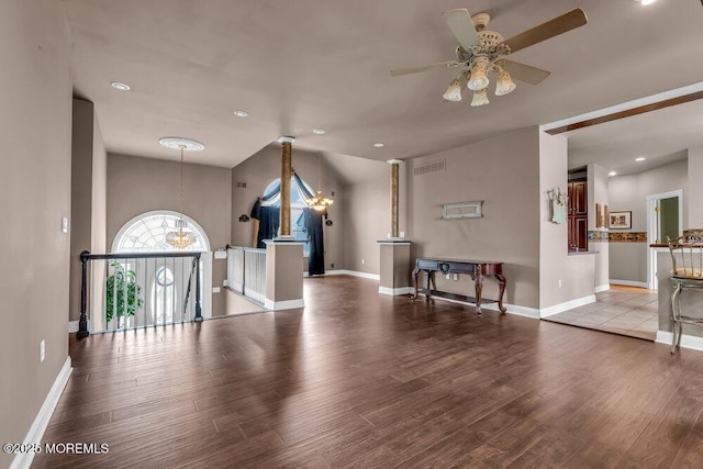 living area featuring baseboards, visible vents, wood finished floors, and ceiling fan with notable chandelier