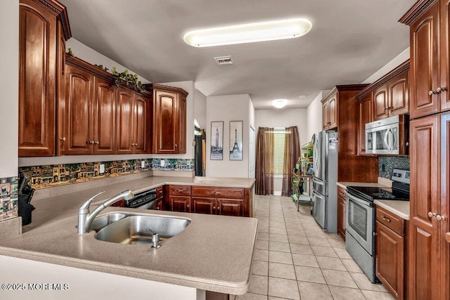 kitchen with appliances with stainless steel finishes, a sink, a peninsula, decorative backsplash, and visible vents