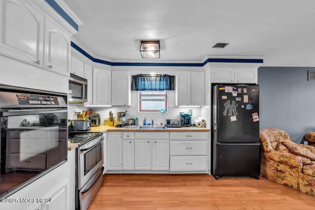 kitchen featuring a sink, white cabinets, and black appliances