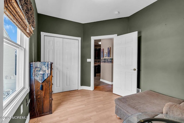 bedroom with a closet, light wood finished floors, and baseboards