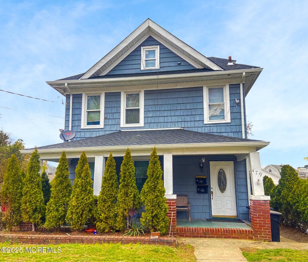 view of front facade featuring roof with shingles and covered porch