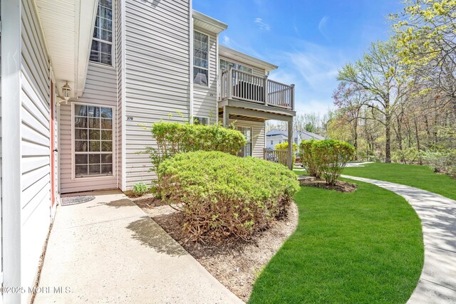 view of side of property featuring a yard and a balcony