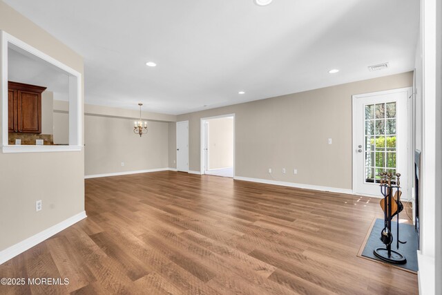 unfurnished living room with recessed lighting, an inviting chandelier, visible vents, light wood-style floors, and baseboards