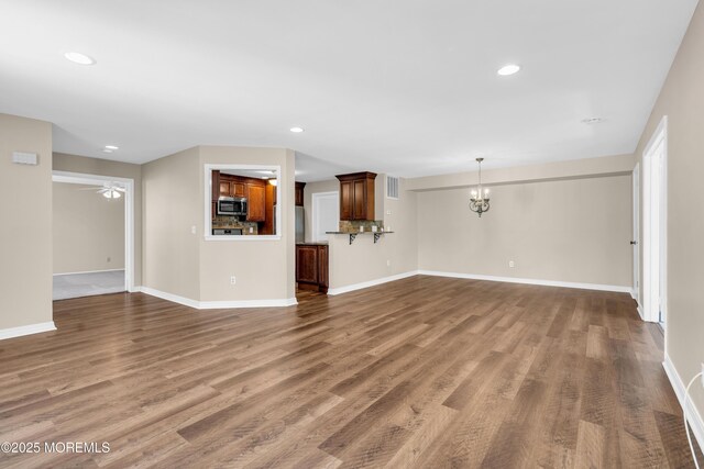 unfurnished living room featuring recessed lighting, wood finished floors, and baseboards