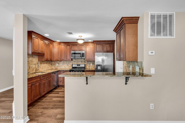 kitchen featuring a peninsula, wood finished floors, stainless steel appliances, and visible vents