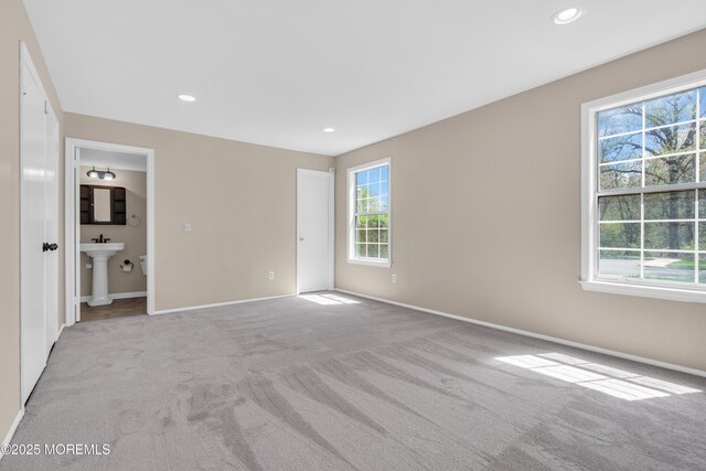 unfurnished bedroom with baseboards, recessed lighting, light colored carpet, and multiple windows