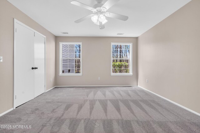 carpeted empty room featuring visible vents, baseboards, and ceiling fan