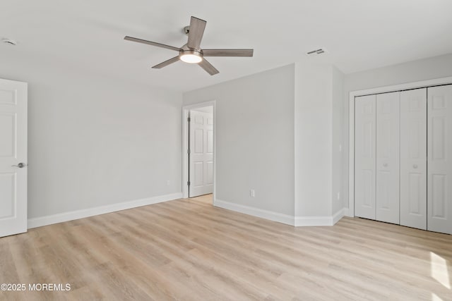 unfurnished bedroom featuring visible vents, a closet, baseboards, light wood finished floors, and a ceiling fan