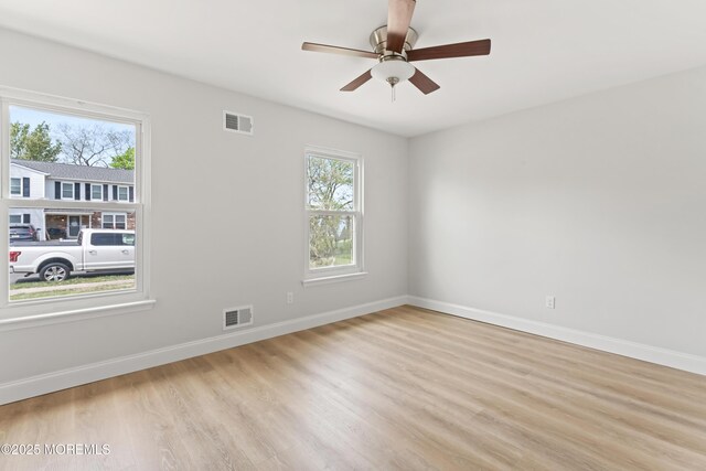 spare room featuring visible vents, light wood-style flooring, and baseboards