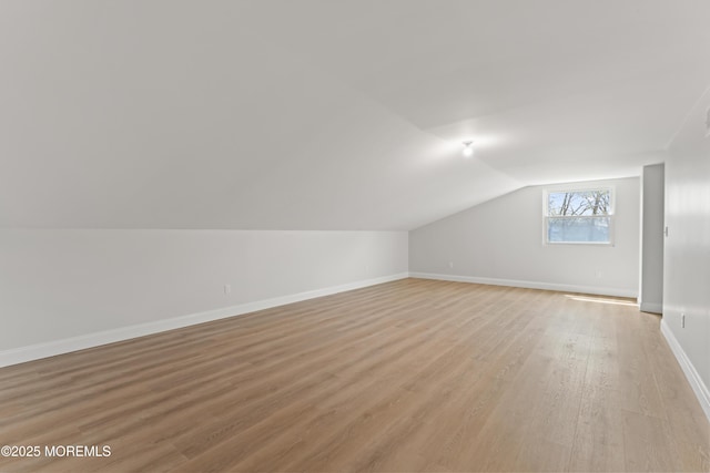 bonus room featuring lofted ceiling, light wood-type flooring, and baseboards
