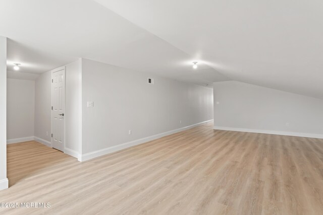 additional living space featuring lofted ceiling, light wood-style floors, visible vents, and baseboards