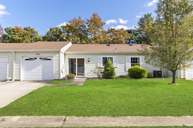 ranch-style home featuring an attached garage, driveway, cooling unit, and a front lawn