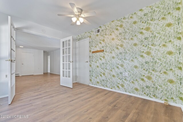 spare room with wood finished floors, wallpapered walls, french doors, baseboards, and visible vents