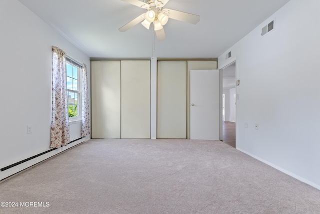 unfurnished bedroom featuring a baseboard radiator, two closets, ceiling fan, carpet floors, and visible vents