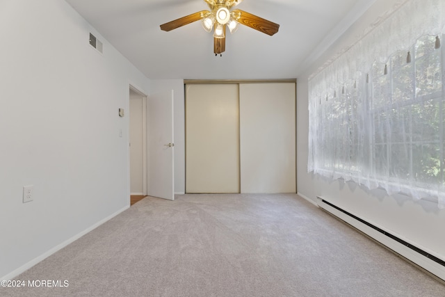 carpeted spare room with a baseboard radiator, a ceiling fan, and visible vents