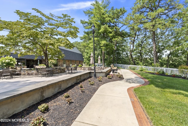 view of home's community with a lawn, a patio, and fence
