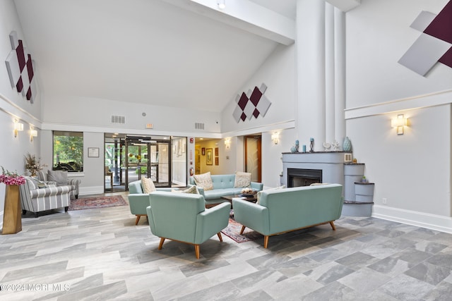 living room featuring high vaulted ceiling, baseboards, visible vents, and a fireplace