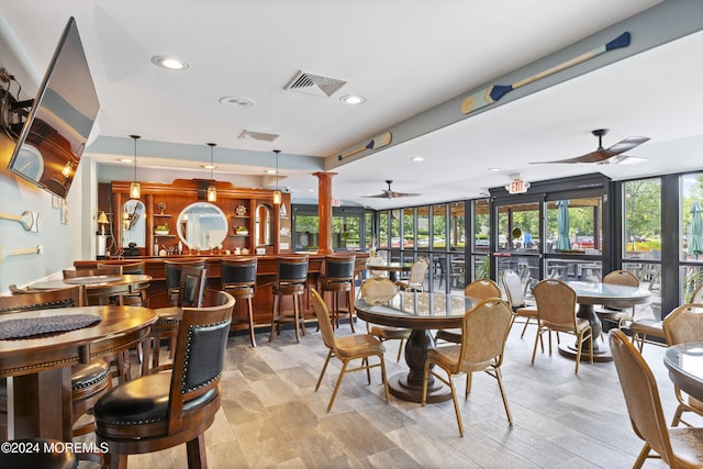 dining space featuring plenty of natural light, a ceiling fan, decorative columns, and a community bar