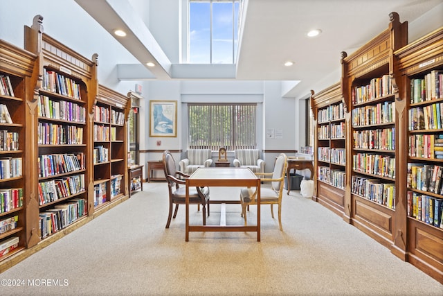 interior space with a towering ceiling, bookshelves, carpet flooring, and recessed lighting
