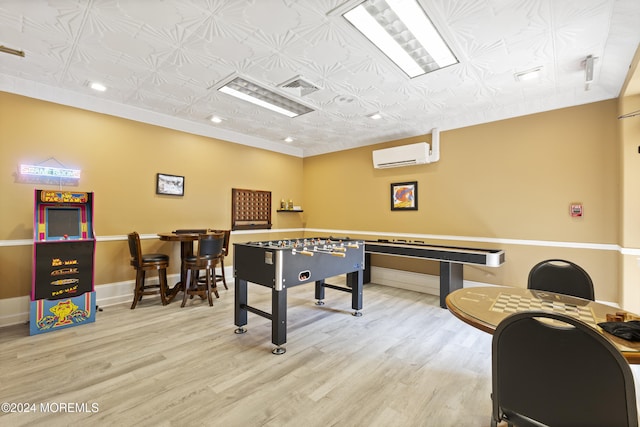 recreation room with an AC wall unit, baseboards, wood finished floors, and visible vents