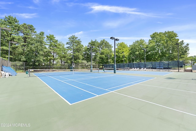 view of tennis court featuring fence and community basketball court