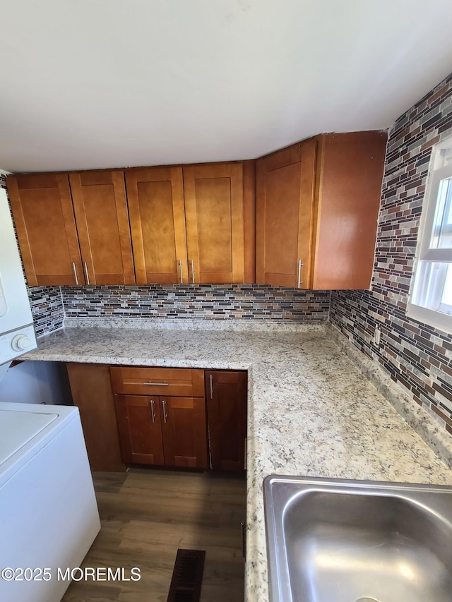28 Alissa Ter, Jackson, NJ 08527 - kitchen with stacked washer and dryer, a sink, brown cabinetry, wood finished floors, and backsplash