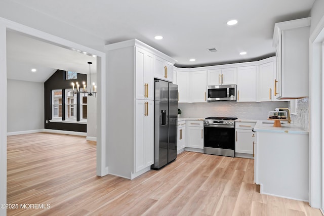 kitchen with light countertops, a chandelier, light wood-style flooring, backsplash, and stainless steel appliances